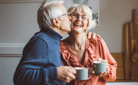 Older couple embracing while holding coffee cups