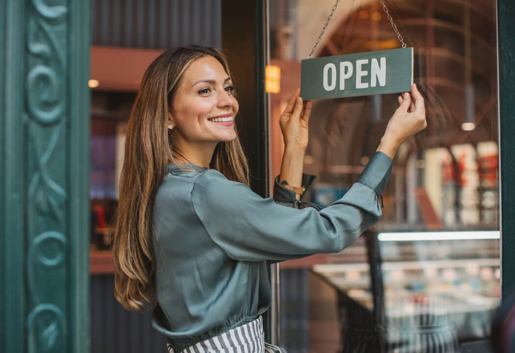 Woman flipping over an "OPEN" sign in front of a business