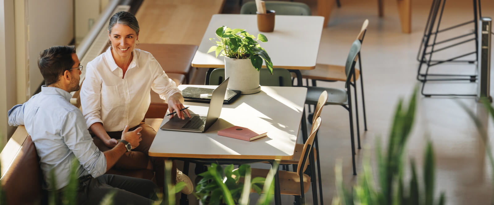 Two people in business casual sitting in a cafe with a laptop