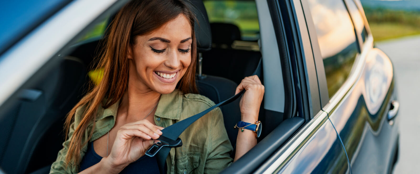 Woman putting on seatbelt in a car